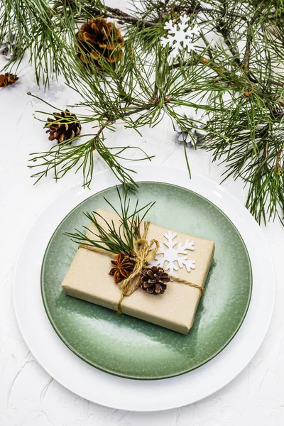 Noel ya da yeni yıl sofrası. Şenlikli çatal bıçak takımı, taze çam dallı seramik tabaklar, koniler, sıfır atık hediye ve yıldız anason. Beyaz macun arkaplanı, kapat