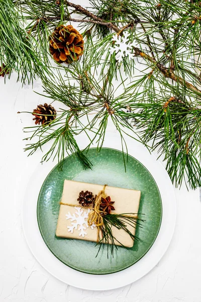 Noel ya da yeni yıl sofrası. Şenlikli çatal bıçak takımı, taze çam dallı seramik tabaklar, koniler, sıfır atık hediye ve yıldız anason. Beyaz macun arkaplanı, kapat
