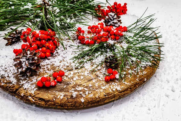 Kırmızı Rowan 'ın eski bir kar kaplı masada olduğu çam tümsekleri ve dallar. Geleneksel kış arkaplanı, kapat