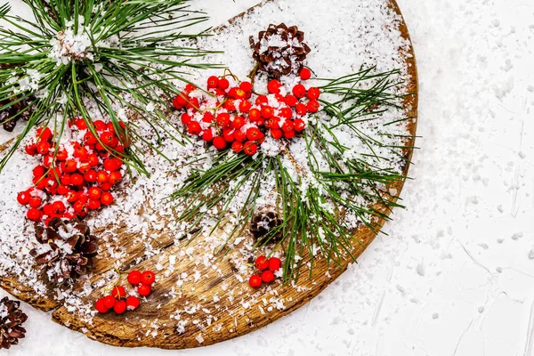 Kırmızı Rowan 'ın eski bir kar kaplı masada olduğu çam tümsekleri ve dallar. Geleneksel kış arkaplanı, kopyalama alanı