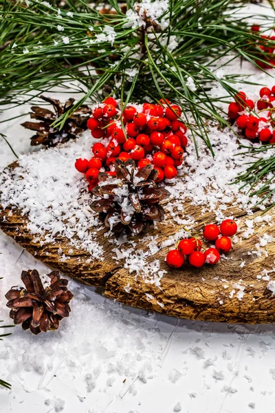 Kırmızı Rowan 'ın eski bir kar kaplı masada olduğu çam tümsekleri ve dallar. Geleneksel kış arkaplanı, kapat