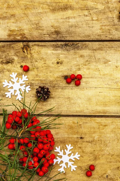 Noel ya da yeni yıl konsepti. Taze çam dalları, olgun yaban mersini, kar taneleri ve çam kozalakları. Eski ahşap zemin, üst manzara