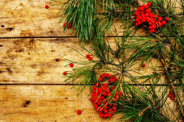 Noel ya da yeni yıl konsepti. Taze çam dalları, olgun yaban mersini, kar taneleri ve çam kozalakları. Eski ahşap zemin, üst manzara