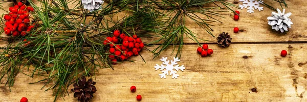 Noel ya da yeni yıl konsepti. Taze çam dalları, olgun yaban mersini, kar taneleri ve çam kozalakları. Eski ahşap arkaplan, pankart biçimi