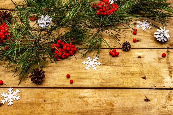 Noel ya da yeni yıl konsepti. Taze çam dalları, olgun yaban mersini, kar taneleri ve çam kozalakları. Eski tahta arkaplan, kopyalama alanı
