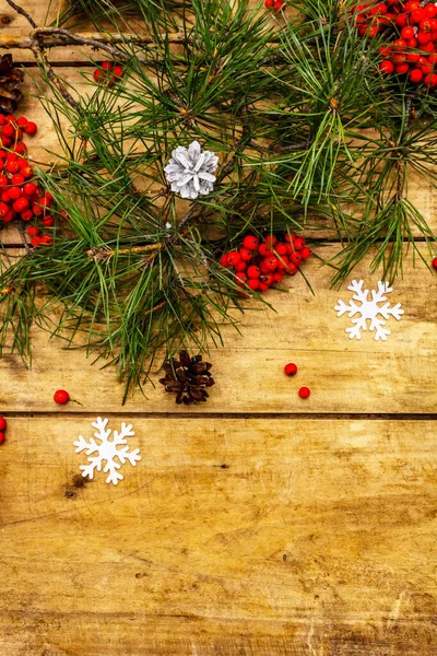 Noel ya da yeni yıl konsepti. Taze çam dalları, olgun yaban mersini, kar taneleri ve çam kozalakları. Eski ahşap zemin, üst manzara