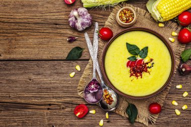Taze sebzeli, otlu ve baharatlı mısır kremalı çorba. Klasik sonbahar sıcak yemeği, eski ahşap tahta arka plan, üst manzara.