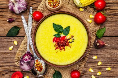 Taze sebzeli, otlu ve baharatlı mısır kremalı çorba. Klasik sonbahar sıcak yemeği, eski ahşap tahta arka plan, üst manzara.