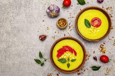 Taze sebzeli, otlu ve baharatlı mısır kremalı çorba. Klasik sonbahar yemeği, taş beton arka plan, üst görünüm.