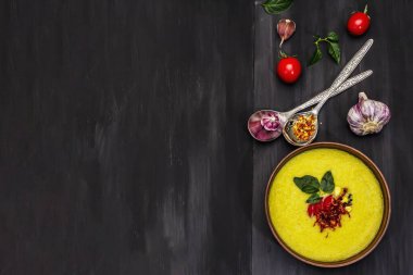 Taze sebzeli, otlu ve baharatlı mısır kremalı çorba. Klasik sonbahar sıcak yemeği, siyah ahşap arka plan, üst manzara.