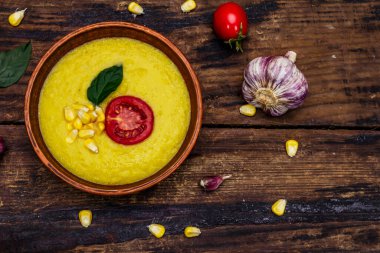 Taze sebzeli, otlu ve baharatlı mısır kremalı çorba. Klasik sonbahar sıcak yemeği, eski ahşap masa, üst manzara.