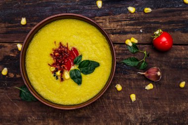 Taze sebzeli, otlu ve baharatlı mısır kremalı çorba. Klasik sonbahar sıcak yemeği, eski ahşap masa, üst manzara.