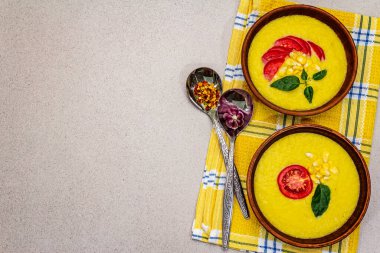Taze sebzeli, otlu ve baharatlı mısır kremalı çorba. Klasik sonbahar yemeği, taş beton arka plan, üst görünüm.