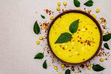 Taze sebzeli, otlu ve baharatlı mısır kremalı çorba. Klasik sonbahar yemeği, taş beton arka plan, üst görünüm.