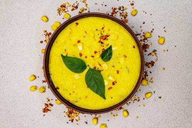 Taze sebzeli, otlu ve baharatlı mısır kremalı çorba. Klasik sonbahar yemeği, taş beton arka plan, üst görünüm.