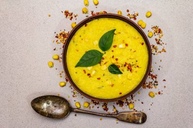Taze sebzeli, otlu ve baharatlı mısır kremalı çorba. Klasik sonbahar yemeği, taş beton arka plan, üst görünüm.