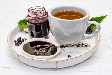 Mürver reçeli, şurup, ziyafet ve sıcak çay. Olgun böğürtlen, tatlı ve sağlıklı tatlı. Alternatif tıp ve yaşam tarzı. Beyaz macun arkaplanı, kapat