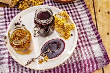 Mürver çayı, kurumuş çiçekler, olgun böğürtlen. Tatlı reçel, şurup ya da konfeksiyon. Sağlıklı tatlı, sıcak içecek. Alternatif tıp ve yaşam tarzı. Eski tahta masa, boşluğu kopyala