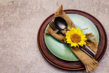 Sonbahar ve Şükran Günü yemeği. Ayçiçeği buketi, seramik tabaklar ve çuval bezi peçete. Taş zemine siyah çatal bıçak takımı, kopyala boşluk