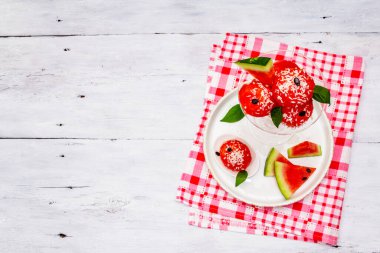 Hindistan cevizi gevreği ve taze fesleğen yapraklı tatlı karpuzlu dondurma. Sağlıklı tatlı, beyaz tahta arka plan, üst manzara.