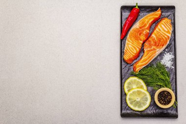 Çiğ Norveç alabalık filetosu. Bir parça taze balık, limon, dereotu, acı biber, tuz. Suşi derecesi, taş beton arka plan