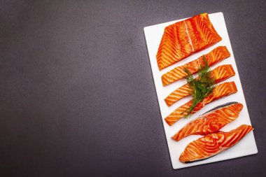 Çiğ Norveç alabalığı. Bir parça taze balık, limon, dereotu, acı biber, tuz. Suşi kalitesi, siyah taş beton arka plan