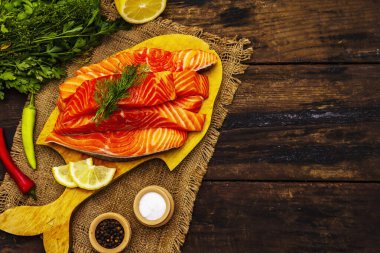 Çiğ Norveç alabalığı. Taze balık parçaları, limon, dereotu, biber, yeşillik, tuz. Eski tahta masa.