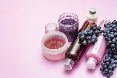 Olgun üzümlü doğal spa aksesuarları. Sağlıklı ve güzel kişisel bakım için taze malzemeler. Pembe arkaplan, kopyalama alanı