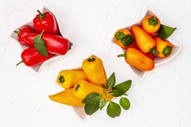 Çok renkli çeşitli bebek biberler: kırmızı, turuncu ve sarı. Taze hasat, sağlıklı yaşam tarzı için sulu ürünler. Beyaz macun arkaplanı, kapat