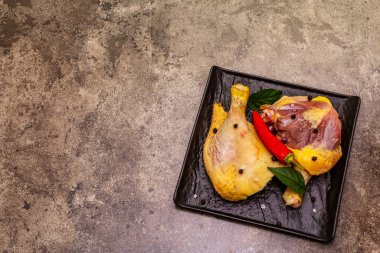 Çiğ çiğ organik tavuk bacağı. Sebze ve baharatlı taze et. Taş beton zemin, üst görünüm