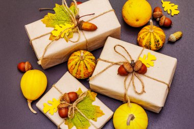 Sıfır atık hediye konsepti. Karton kutular, mini balkabakları, meşe palamutları ve dökülen yapraklarla yaratıcı bir sonbahar dekoru. Şükran Günü ya da Cadılar Bayramı siyah taş arka plan kavramı, kapat