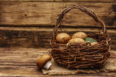 Kahverengi kraliyet şampiyonu mantarları el yapımı hasır sepette. Eski kırsal masada sağlıklı bir yaşam için işlenmemiş malzeme, kopyalama alanı.