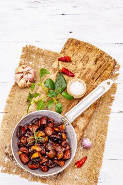 Kadife tavada kızarmış kahverengi şampiyonları yemeye hazır. Baharatlı ve taze otlu kraliyet mantarları. Eski beyaz ahşap masa, üst manzara.