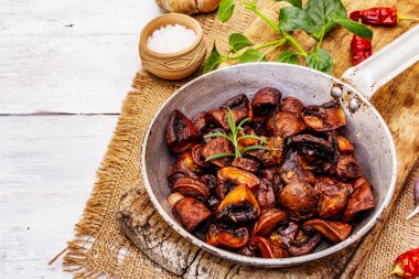 Kadife tavada kızarmış kahverengi şampiyonları yemeye hazır. Baharatlı ve taze otlu kraliyet mantarları. Eski beyaz ahşap masa, yaklaşın.