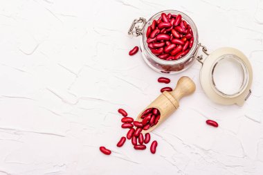 Kuru fasulye ya da cam kavanozda böbrek fasulyesi. Sağlıklı bir vegan diyeti için değerli bir protein kaynağı. Beyaz macun arkaplan, üst görünüm