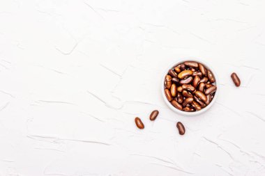 Kuru kahverengi fasulye ya da cam kavanozda böbrek fasulyesi. Sağlıklı bir vegan diyeti için değerli bir protein kaynağı. Beyaz macun arkaplan, üst görünüm