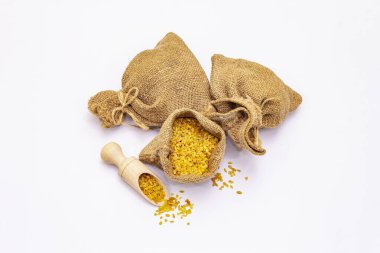 Bulgur taneleri beyaz arka planda izole edilmiş. Sağlıklı yemek hazırlamada kullanılan geleneksel bir bileşen. Tahta kepçe ve el yapımı çuvallar.