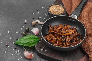 Tavada sarımsak, fesleğen ve baharatla kızartılmış Shimeji mantarı. Koyu bir arka planda, ahşap bir tahtayla servis ediliyor. Vejetaryen yaşam tarzı konsepti, düz konum, kopyalama alanı