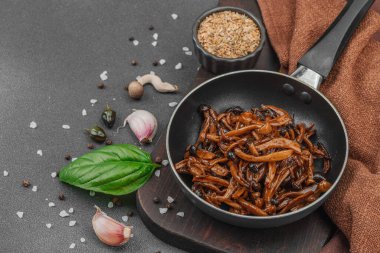 Tavada sarımsak, fesleğen ve baharatla kızartılmış Shimeji mantarı. Koyu bir arka planda, ahşap bir tahtayla servis ediliyor. Vejetaryen yaşam tarzı konsepti, düz konum, kopyalama alanı