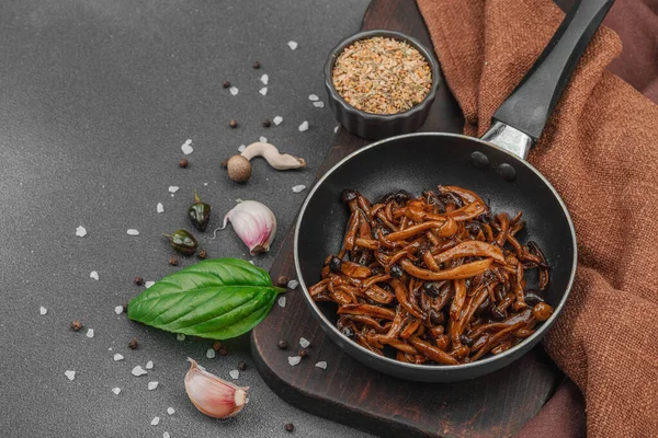 Tavada sarımsak, fesleğen ve baharatla kızartılmış Shimeji mantarı. Koyu bir arka planda, ahşap bir tahtayla servis ediliyor. Vejetaryen yaşam tarzı konsepti, düz konum, kopyalama alanı