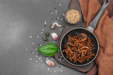 Tavada sarımsak, fesleğen ve baharatla kızartılmış Shimeji mantarı. Koyu bir arka planda, ahşap bir tahtayla servis ediliyor. Vejetaryen yaşam tarzı konsepti, düz yatak, üst manzara