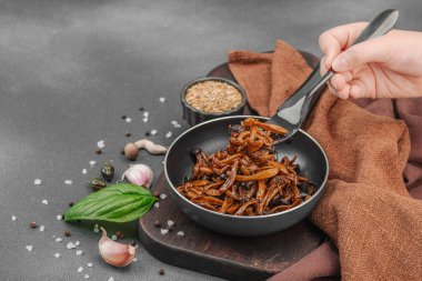 Tavada sarımsak, fesleğen ve baharatla kızartılmış Shimeji mantarı. Koyu bir arka planda, ahşap bir tahtayla servis ediliyor. El çatal, vegan yaşam tarzı konsepti, kopyalama alanı