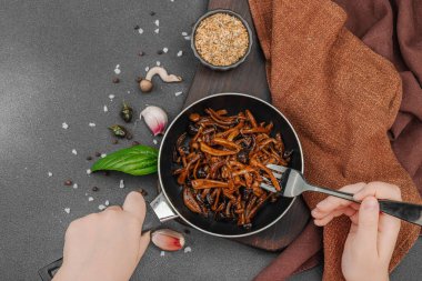 Tavada sarımsak, fesleğen ve baharatla kızartılmış Shimeji mantarı. Koyu bir arka planda, ahşap bir tahtayla servis ediliyor. El çatal, vejetaryen yaşam tarzı konsepti, üst görünüm.