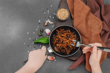 Tavada sarımsak, fesleğen ve baharatla kızartılmış Shimeji mantarı. Koyu bir arka planda, ahşap bir tahtayla servis ediliyor. El çatal, vejetaryen yaşam tarzı konsepti, üst görünüm.