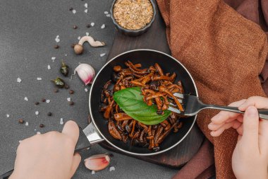 Tavada sarımsak, fesleğen ve baharatla kızartılmış Shimeji mantarı. Koyu bir arka planda, ahşap bir tahtayla servis ediliyor. El çatal, vejetaryen yaşam tarzı konsepti, üst görünüm.