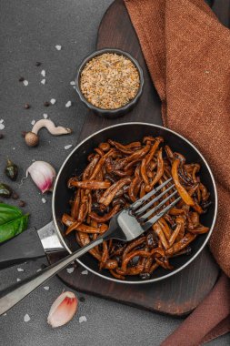 Tavada sarımsak, fesleğen ve baharatla kızartılmış Shimeji mantarı. Koyu bir arka planda, ahşap bir tahtayla servis ediliyor. Vejetaryen yaşam tarzı konsepti, düz yatak, üst manzara