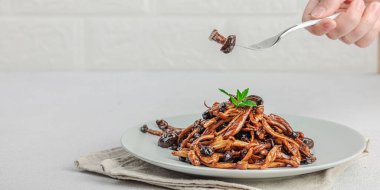 Fırında Shimeji mantarı, baharat ve otlarla dolu bir tabakta. El çatal, vejetaryen yaşam tarzı konsepti, hafif doğal arka plan, düz yatak, pankart biçimi