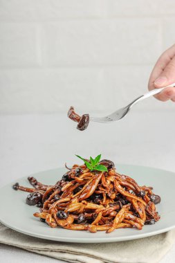 Fırında Shimeji mantarı, baharat ve otlarla dolu bir tabakta. El çatal, vejetaryen yaşam tarzı konsepti, hafif doğal arka plan, düz alan, kopyalama alanı