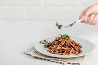 Fırında Shimeji mantarı, baharat ve otlarla dolu bir tabakta. El çatal, vejetaryen yaşam tarzı konsepti, hafif doğal arka plan, düz alan, kopyalama alanı