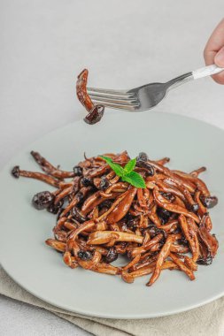 Fırında Shimeji mantarı, baharat ve otlarla dolu bir tabakta. El çatal, vejetaryen yaşam tarzı konsepti, hafif doğal arka plan, düz alan, kopyalama alanı